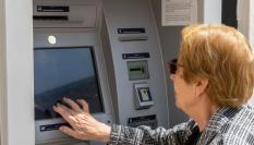 Una mujer de la tecera edad utilizando un cajero.