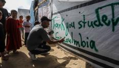 Un palestino hace una pintada en una tienda de campaña en Rafah en agradecimiento a las protestas estudiantiles en Estados Unidos.
