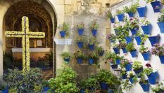 Un patio cordobés con una cruz de mayo elaborada con flores.