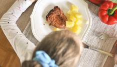 Imagen de archivo de una niña comiendo pescado.