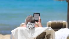 Un turista toma el sol mientras lee en una playa de Mallorca.