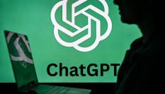 Una mujer sostiene un portátil delante de un logotipo de ChatGPT.