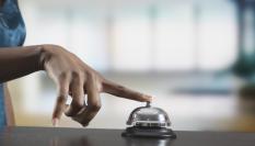 Imagen de archivo de una persona tocando el timbre en la recepción de un hotel.