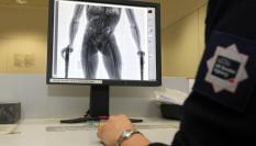 Un agente de fronteras de Reino Unido analiza la radiografía tomada a un sospechoso de haber ingerido drogas.