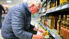Un cliente mirando el precio del aceite de oliva en el supermercado.