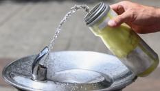 Una persona llena de agua su botella en una fuente pública.