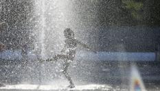 Una niña juega en una fuente