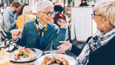 Dos amigas comiendo en una terraza.