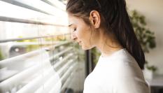 Imagen de archivo de una mujer angustiada junto a la ventana.