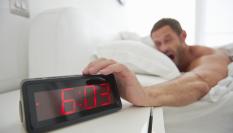 Un hombre apagando la alarma del despertador.