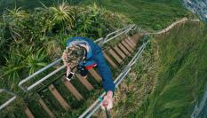 Un joven asciende mirando el móvil por las Escaleras Haiku, en la isla de Oahu, Hawái.