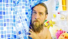 Un hombre se asoma por las cortinas de la ducha.