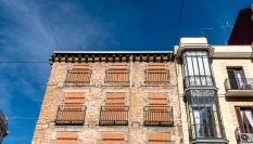 Antiguo edificio con las ventanas tapiadas para evitar las entradas de los okupas.