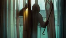 Imagen de una persona encapuchada entrando en una vivienda.