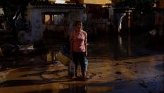 Una mujer que lleva agua embotellada camina por el barro en una calle de Alfafar.