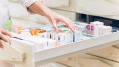 Una farmacéutica coge uno de los medicamentos que vende.