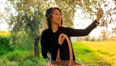 Imagen de una mujer recogiendo aceitunas.