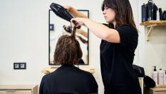 Una peluquera peina a una de sus clientas.