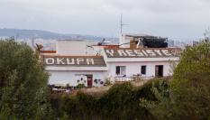 El popular grafiti 'Okupa y Resiste' que se puede ver en el tejado de una vivienda próxima al Parc Güell, en Barcelona.