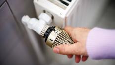Una mujer sube la temperatura de un radiador conectado a una calefacción de gas.