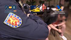 Uno de los agentes custodia a uno de los detenidos durante uno de los registros practicado.