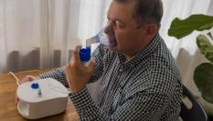 Un hombre usa un nebulizador.