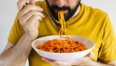 Un hombre comiendo un plato de pasta.