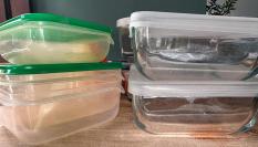 Tuppers de plástico y de cristal encima de una mesa de madera.