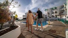 Una pareja de turistas pasa junto a la piscina de una urbanización en Callao Salvaje, Tenerife.