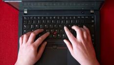 Una mujer que teletrabaja escribe en su portátil de empresa.