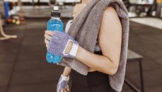 Una chica en un gimnasio bebe una bebida energética.