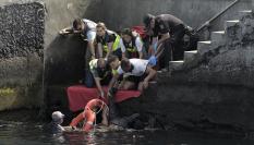 Personal de emergencias asiste a los ocupantes de un cayuco volcado en el puerto de La Restinga (El Hierro, Canarias), cuando iban a desembarcar.