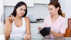 Imagen de archivo de una madre dando dinero a su hija adolescente.