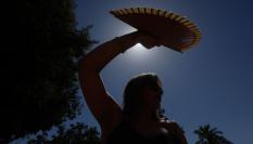 Una mujer se protege con un abanico del sol en Córdoba.