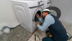 Un técnico reparando o montando una lavadora en una casa.