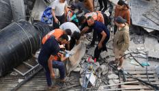 Un grupo de palestinos trabajan entre escombros para recuperar un cuerpo en una casa alcanzada por un ataque israelí, en la ciudad de Gaza.