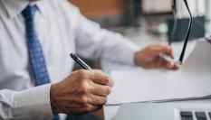 Imagen de una persona firmando un documento en un despacho.