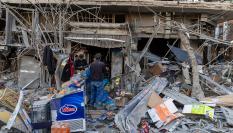 Ciudadanos de Teherán, la capital de Irán, revisan los daños causados en una tienda y una vivienda por los ataques aéreos de EEUU e Israel, 2 de marzo de 2026.