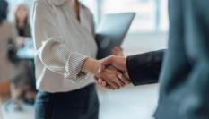 Primer plano de dos empresarios de pie en una oficina dándose la mano