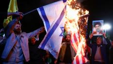 Un hombre sostiene una foto del líder supremo de Irán, Mojtaba Lamenei, mientras se queman banderas de EEUU e Israel, el 8 de abril de 2026 en Teherán, tras conocerse el alto el fuego en Irán.