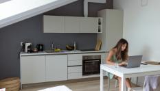 Imagen de una mujer en un estudio, con un colchón al lado de la cocina.