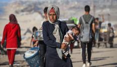 Una mujer palestina carga a su bebé mientras huye del norte de la franja tras los intensos ataques israelíes, en la ciudad de Gaza, el 1 de octubre de 2025.