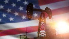 Ilustración de una planta petrolera, con la bandera de EEUU al fondo.