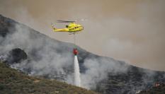 Un helicóptero del servicio de extinción de incendios arroja agua sobre uno de los focos del incendio forestal declarado en Los Gallardos, Almería.
