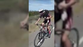 Un ciclista rescata a un perro cargándolo en la espalda