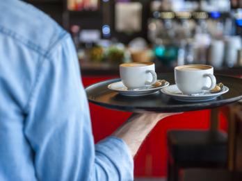Un camarero, llevando dos cafés en una bandeja.