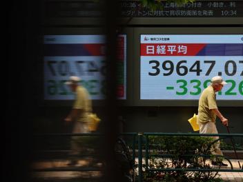 Un hombre pasa delante de una pantalla con las cotizaciones de las acciones del índice  Nikkei, en la bolsa de Tokio.