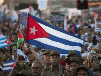 Miles de cubanos enarbolan su bandera nacional, entre militares del ejército revolucionario, en la marcha del Primero de Mayo de 2024, en La Habana.