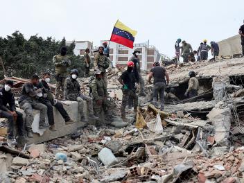 Los equipos de rescate colocan una bandera de Venezuela sobre los escombros, tras el doble terremoto sufrido por el país, el 28 de junio de 2026, en Caracas.