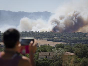 Un hombre observa la columna de humo del incendio forestal que se ha declarado en La Bisbal d'Empordà (Girona).